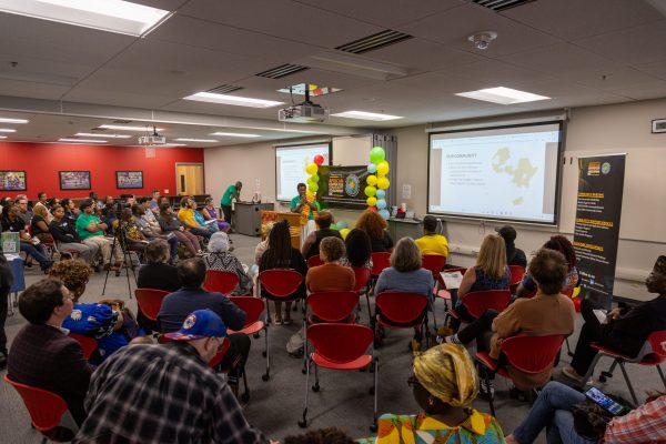 The Executive Director of the African Center, Ama Ptak addressing a large seated audience during an awareness talk in 2025 at their UW South Madison Partnership office.